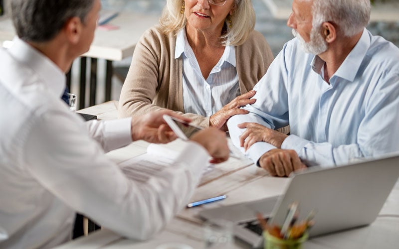 An older couple meets with a professional to discuss financial documents.