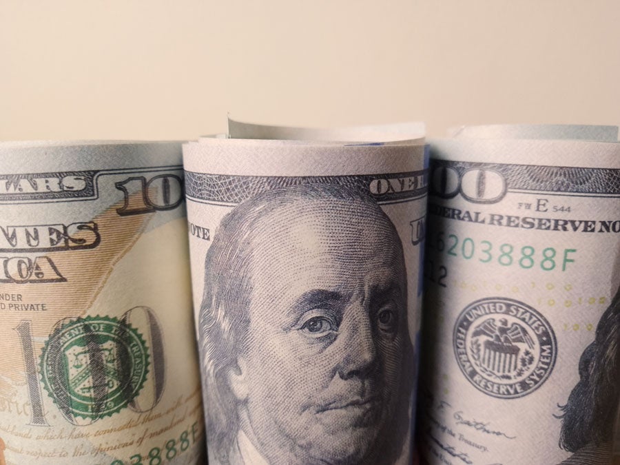 Three rolls of United States hundred-dollar bills stand side by side